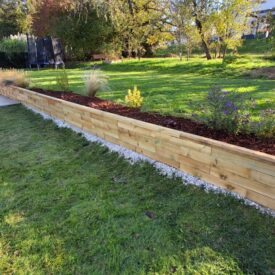 Støttemur med trappe, der forbinder terrasse og græsplæne